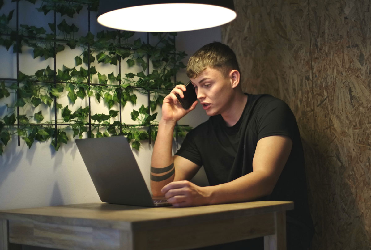 Coach sidder ved et skrivebord, imens han taler i telefon